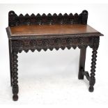 An early 20th century oak side table with carved galleried back, length 104cm.