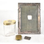 Four items comprising a hallmarked silver photograph frame, a silver topped dressing table bottle, a