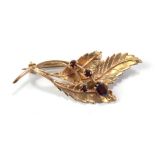 A 9ct yellow gold leaf brooch set with four dark red coloured stones, width 5cm, approx 5.7g.