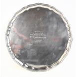 A George V hallmarked silver salver of shaped circular form and raised on four scrolling supports,