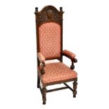 A large early 20th century oak elbow chair, the back with carved floral detail and crest bearing