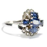 A white metal oval cut sapphire and diamond crossover cluster ring, the band stamped 18k to