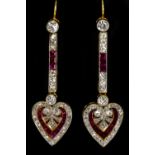 A pair of yellow metal diamond and ruby drop earrings, with upper bar above a heart shaped drop,