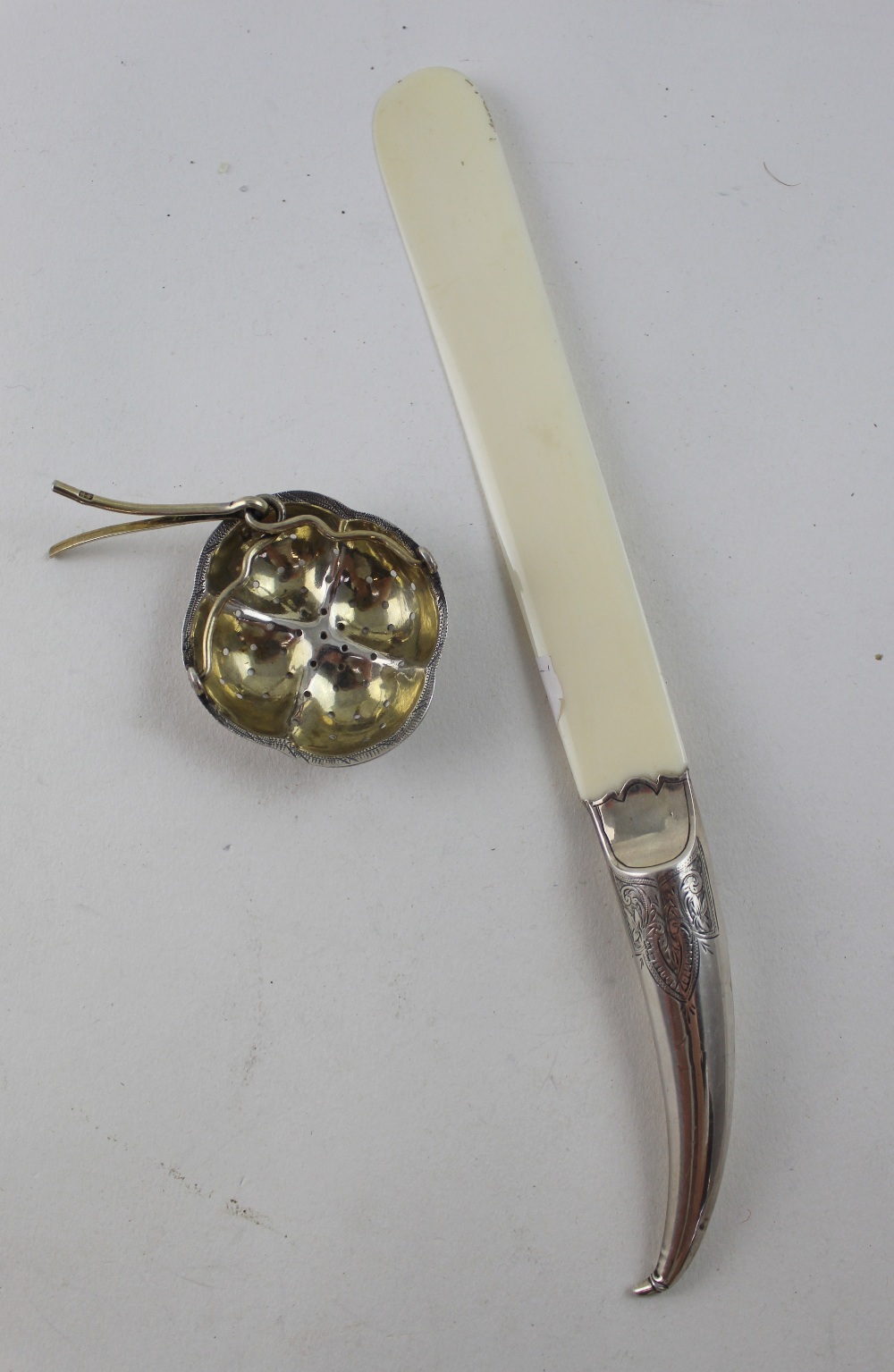 A Russian hallmarked silver tea strainer and an ivory page turner with white metal handle in the