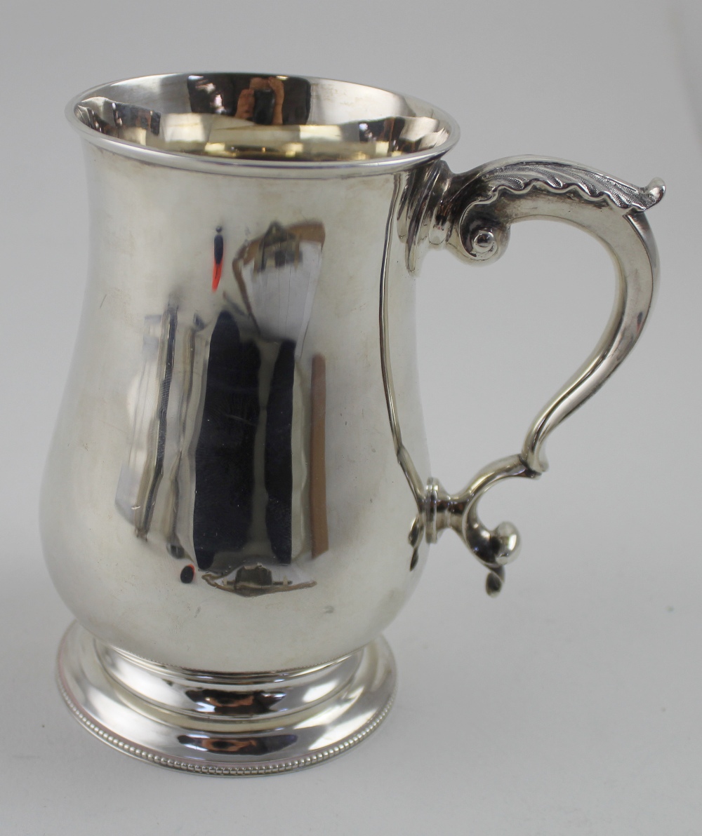 A Victorian hallmarked silver mug of baluster form with C-scroll handle on stepped circular