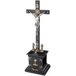 KruzifixDatiert 1906. Kreuz und Sockel aus ebonisiertem Holz. Korpus, Assistenzfiguren und Beschläge