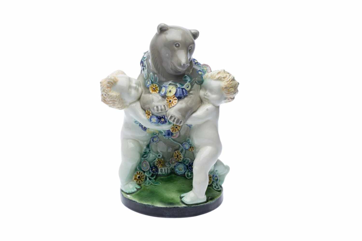 M. Powolny, Bär mit 2 PuttiEin kleiner Bär auf einem runden Sockel stehend wird von 2 Putti