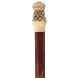 A 19TH CENTURY WALKING CANE, the ivory handle carved with reeded and fretted cagework in the Indo-