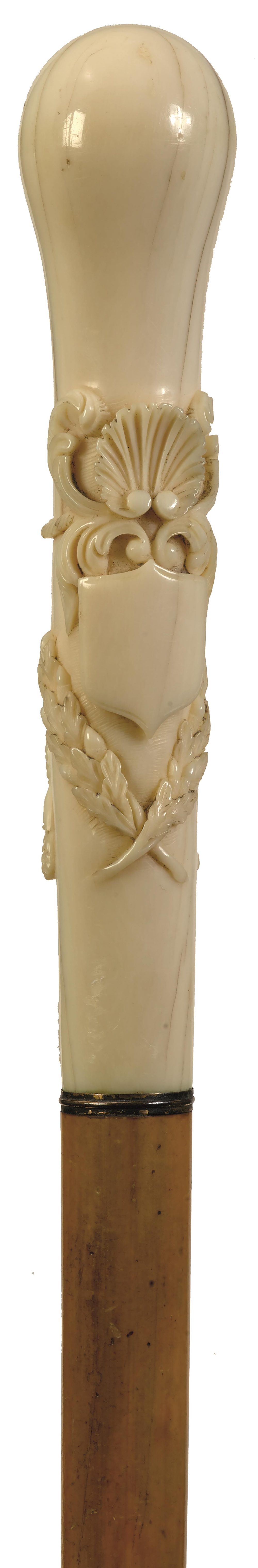 A LATE 19TH CENTURY WALKING CANE, the ivory handle of slender bulbous form and carved in relief with