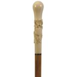 A LATE 19TH CENTURY WALKING CANE, the ivory handle of slender bulbous form and carved in relief with