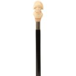A LATE 19TH CENTURY WALKING CANE, the ivory handle carved as a young boy wearing a bicorn hat, above