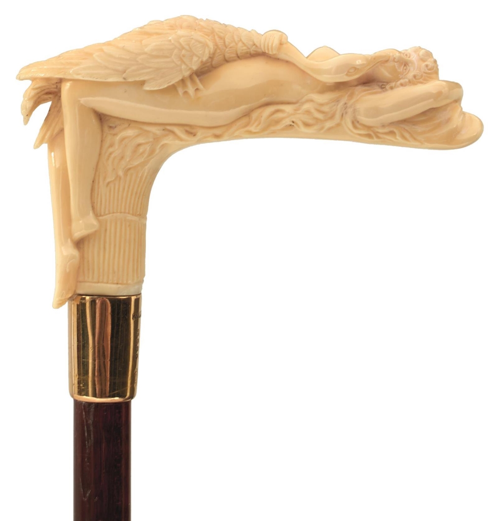 AN EARLY 20TH CENTURY WALKING CANE, the ivory candle carved as Leda and the Swan, above 18ct gold