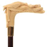 AN EARLY 20TH CENTURY WALKING CANE, the ivory candle carved as Leda and the Swan, above 18ct gold