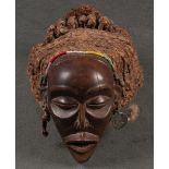 Pwe-Maske. Afrika. Massivholz, geschnitzt und appliziert mit Pflanzenfasern, Glasperlen und Messing,