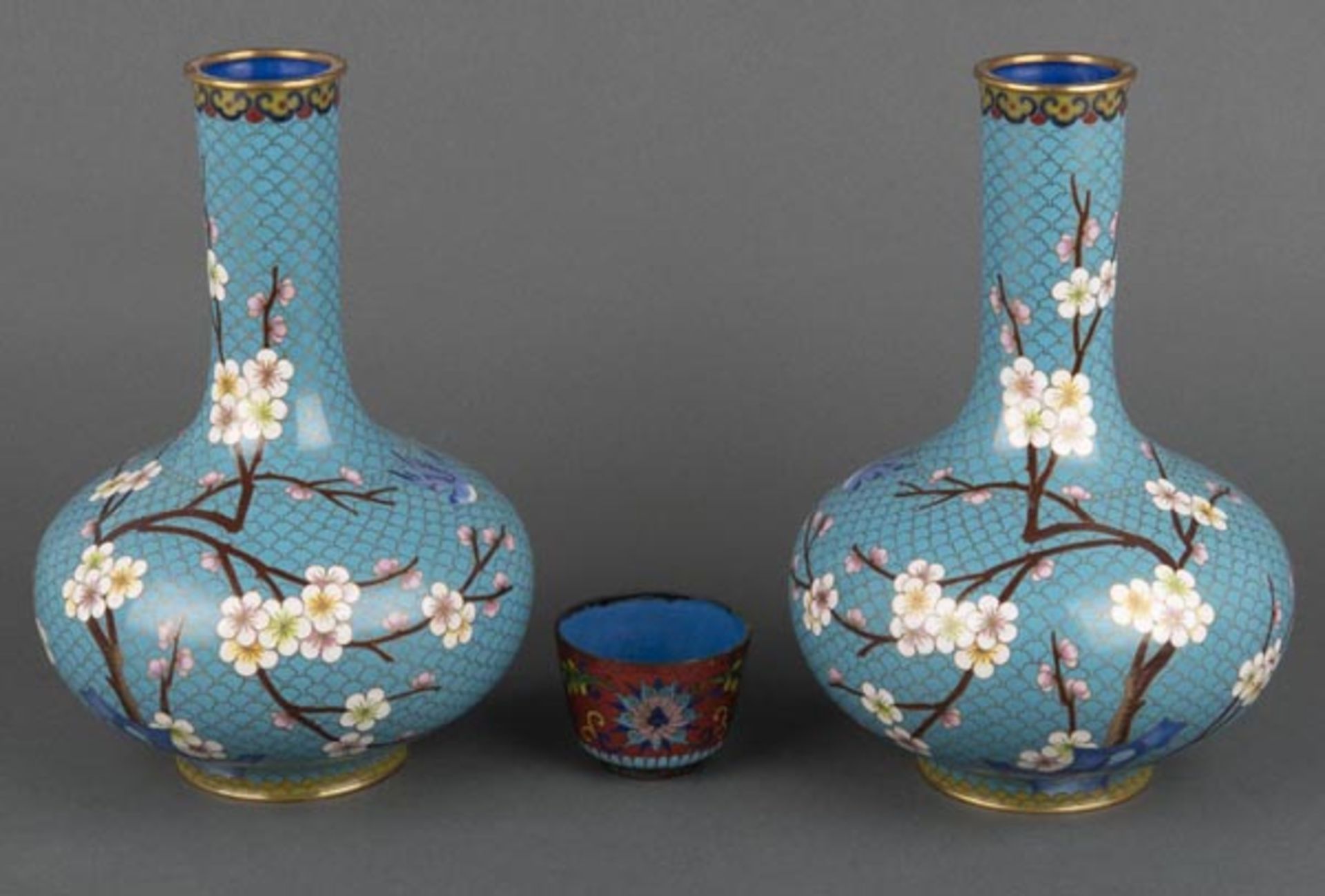 Paar Cloisonné-Vasen. China. Mit bunten Mandelblütenzweigen auf hellblauem Fond; dazu Becher, H=25,5