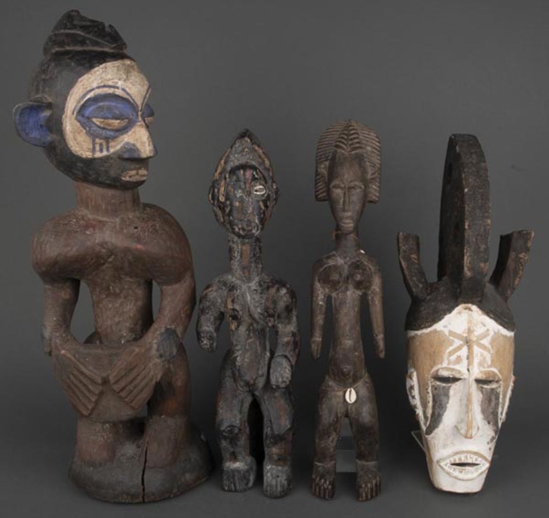 Drei Figuren und eine Maske. Afrika. Massivholz, geschnitzt, teilw. farbig gefasst, H=46 bis 62 cm.