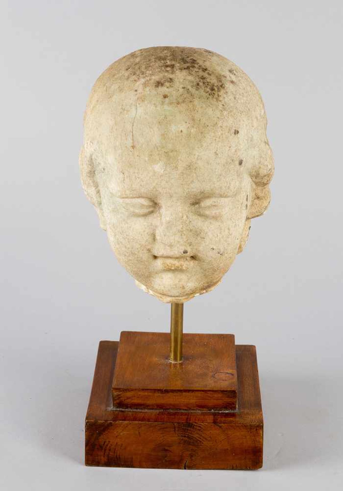 Roman Marble bust of a young boy or child. White marble on later wooden base. Weathered. Possibly