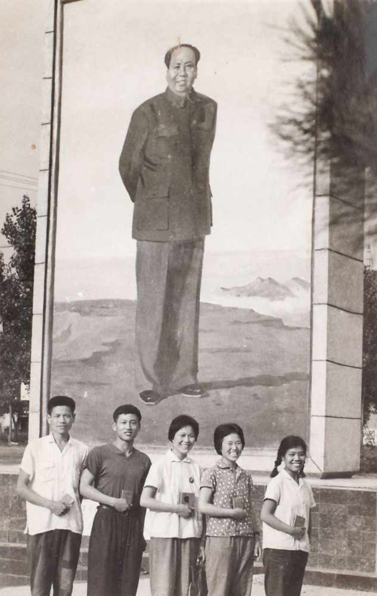 Young pioneers holding the "Little Red Book" next to an impressive board of Mao Zedong, the Cultural