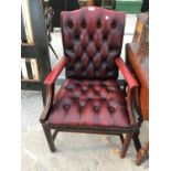 AN OXBLOOD LEATHER AND MAHOGANY ARMCHAIR WITH BUTTONED SEAT AND BACK
