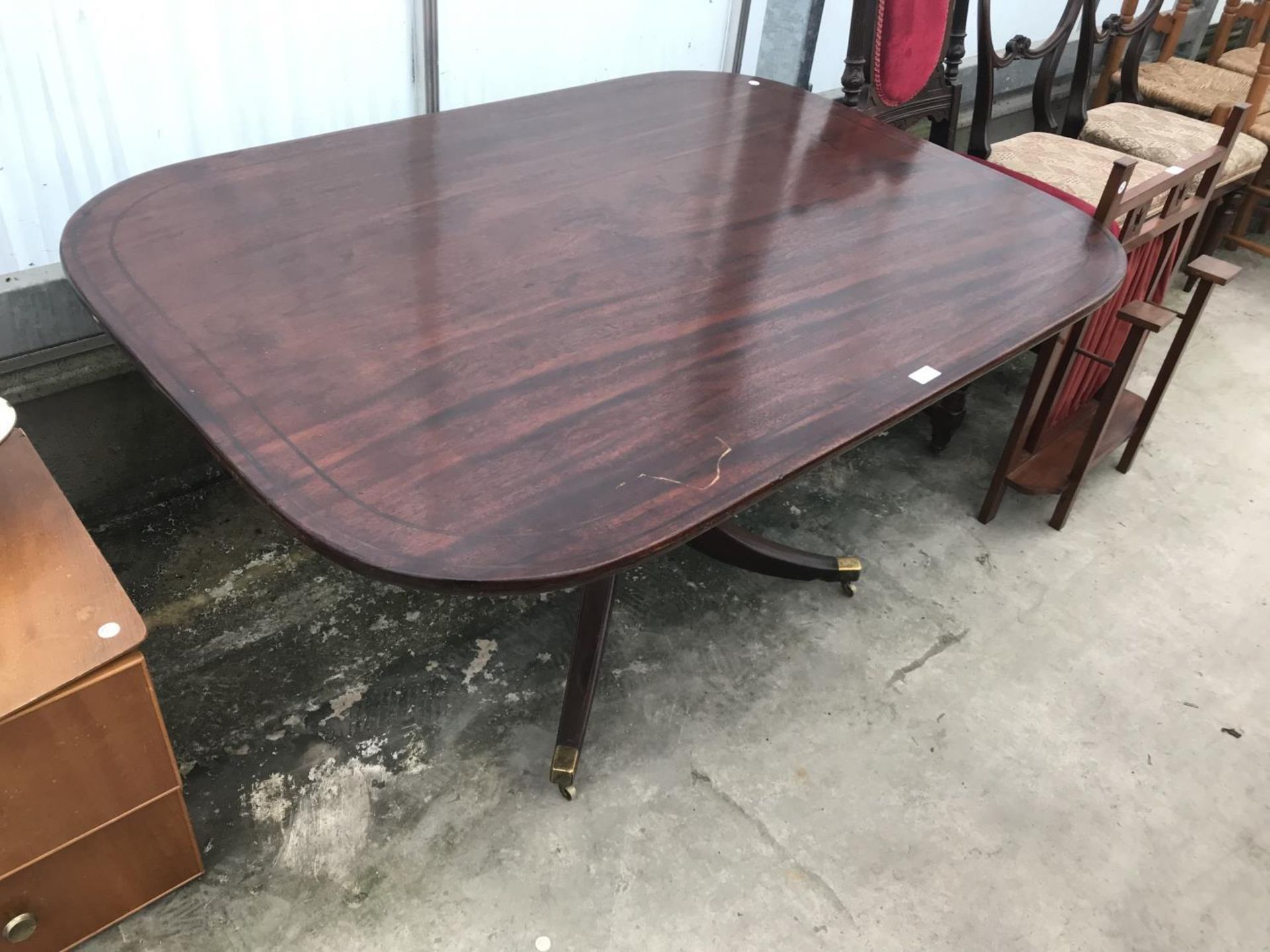 A MAHOGANY DINING TABLE ON TURNED AND CARVED CENTRE PEDESTAL SUPPORT WITH BRASS LION'S PAW FEET ON