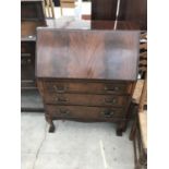 A MAHOGANY BUREAU ON BALL AND CLAW FEET WITH FALL FRONT AND THREE DRAWERS