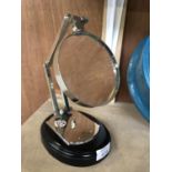 A CHROME MAGNIFYING GLASS ON WOODEN BASE