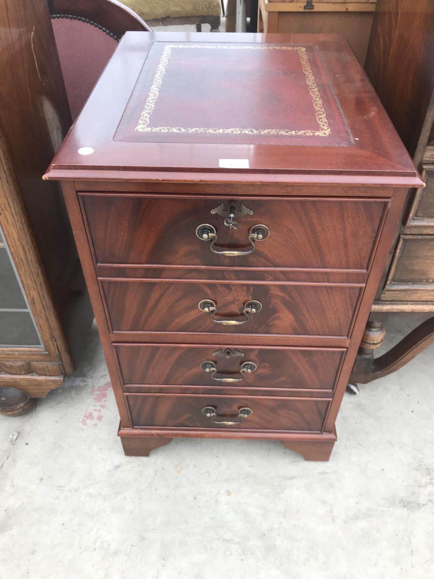 A MAHOGANY FILING CABINET WITH THREE DRAWERS AND RED LEATHER TOP