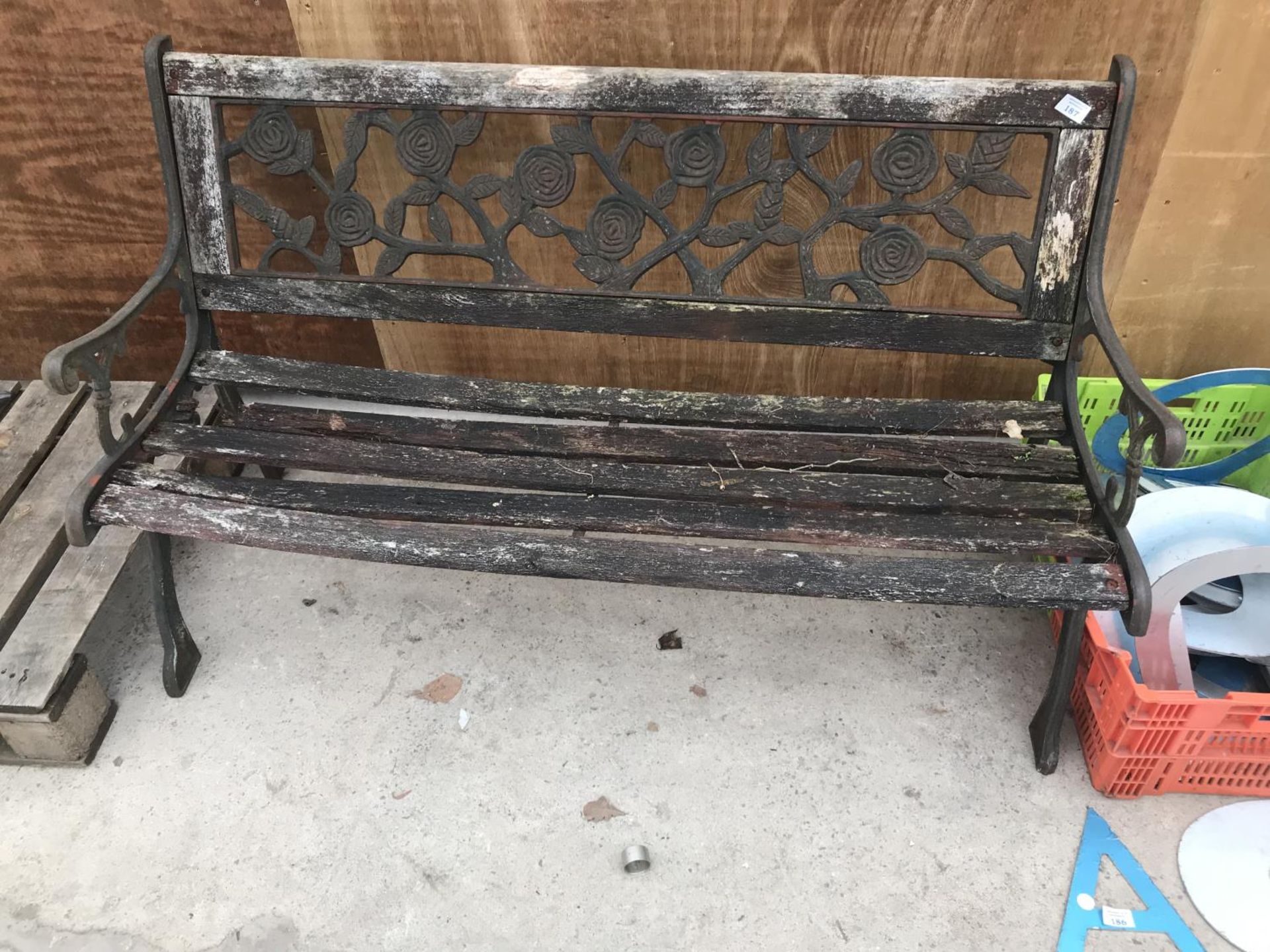 A WOODEN BENCH WITH CAST IRON ENDS AND ROSE DESIGN BACK PANEL 126CM LONG (WOOD NEEDS REPLACING)