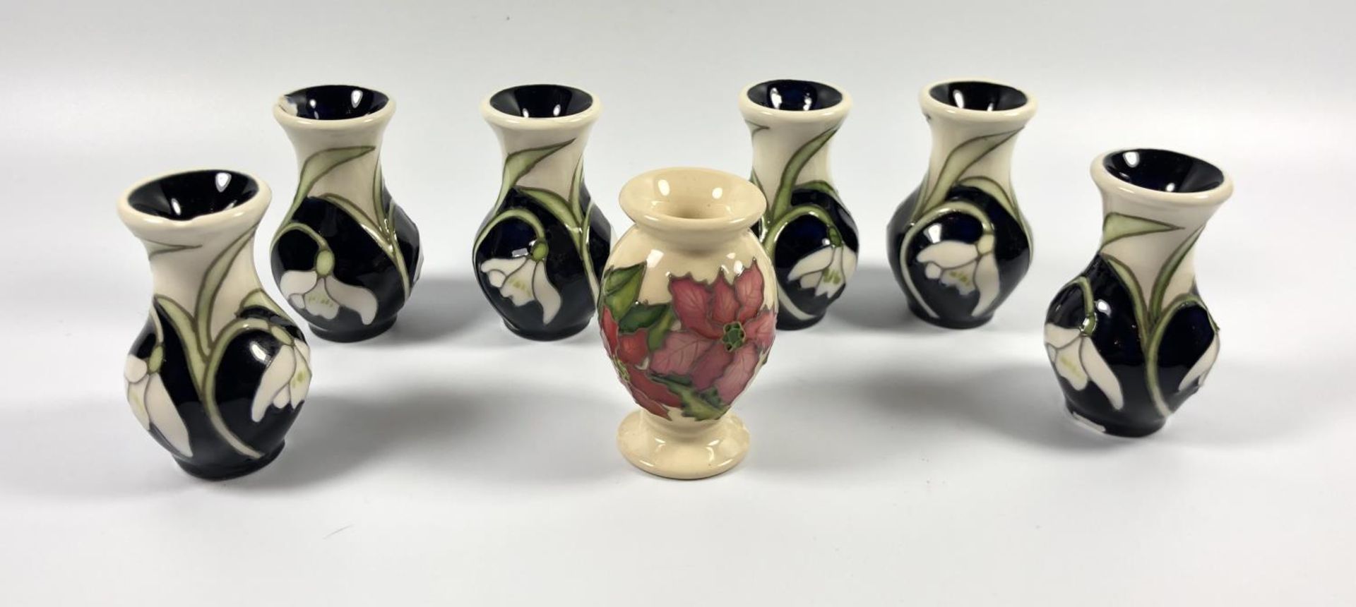 SEVEN ASSORTED MOORCROFT MINIATURE VASES - SIX SNOWDROPS AND ONE POINSETTA, ALL WITH CHIPS