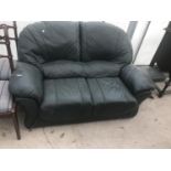 A GREEN LEATHER TWO SEATER SOFA AND FOOTSTOOL