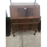 A MAHOGANY BUREAU ON CABRIOLE SUPPORTS AND BALL AND CLAW FEET WITH FALL FRONT AND THREE DRAWERS