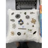 A CUSHION OF ASSORTED COSTUME JEWELLERY BROOCHES