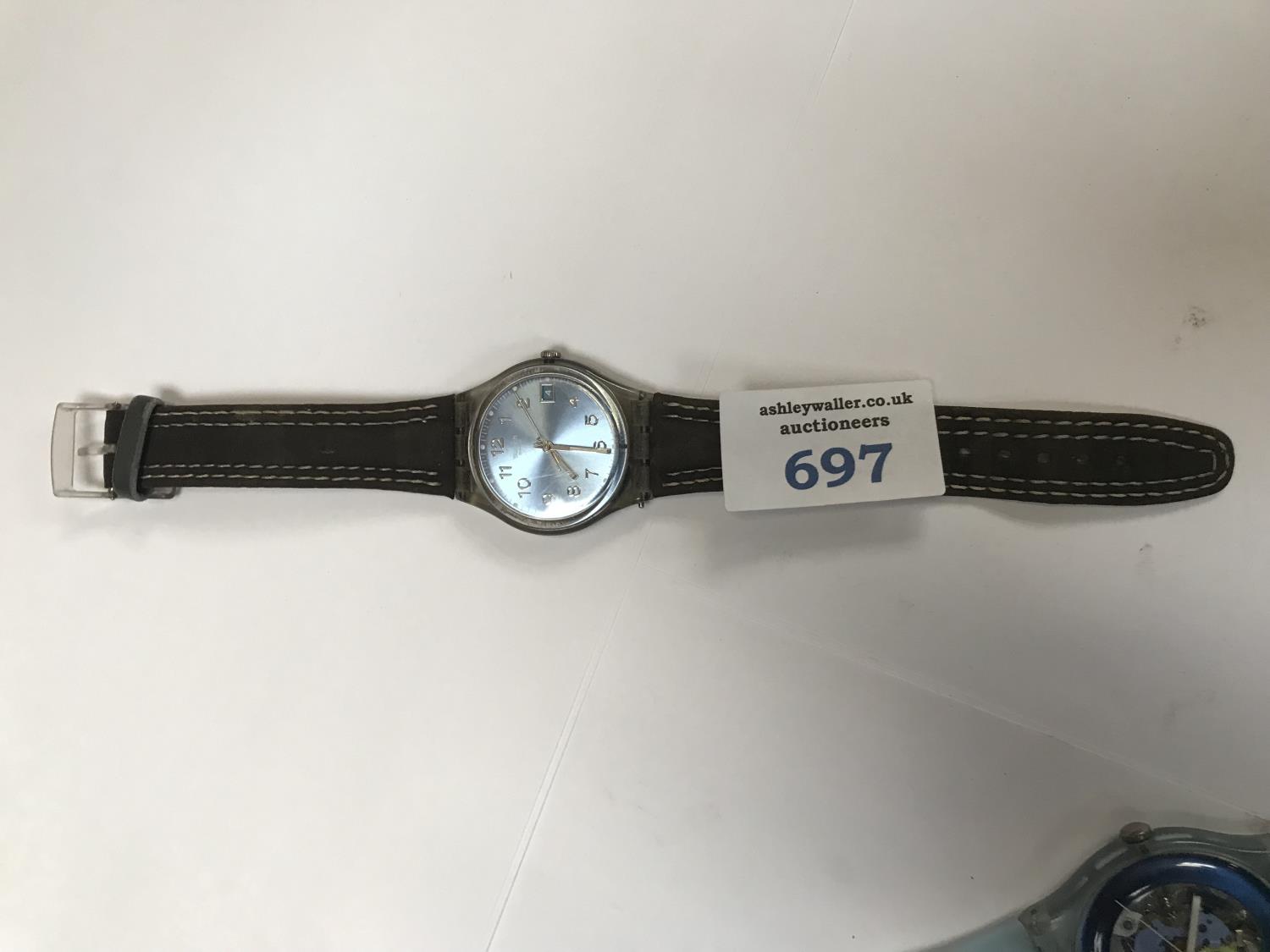 A SWATCH WATCH WITH A BLUE FACE AND A BROWN SUEDE STRAP.