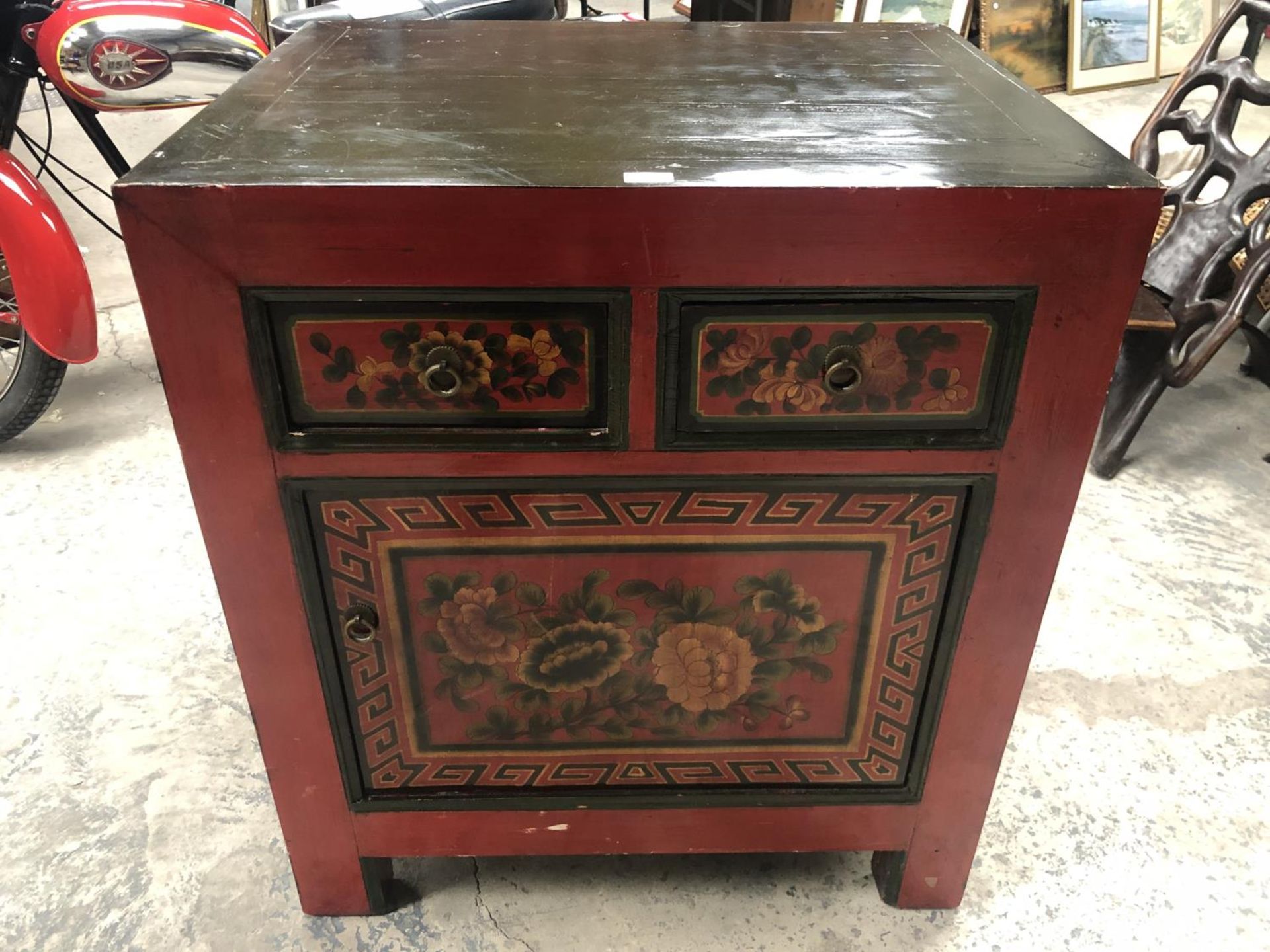 AN ORIENTAL RED LACQUERED CABINET WITH TWO DRAWERS AND LOWER DOOR