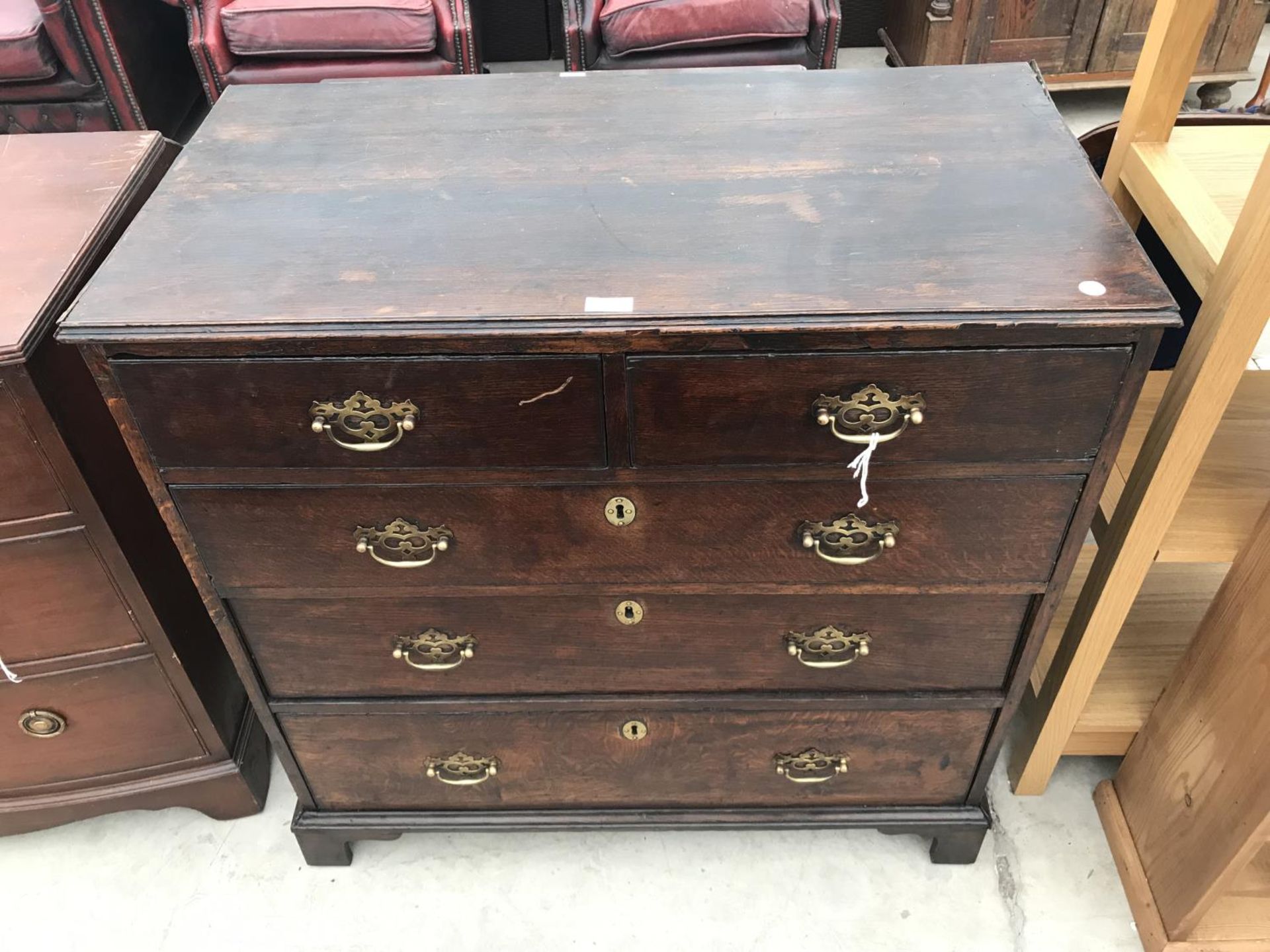 AN OAK CHEST OF TWO SHORT AND THREE LONG DRAWERS WITH ORNATE BRASS HANDLES ON BRACKET FEET
