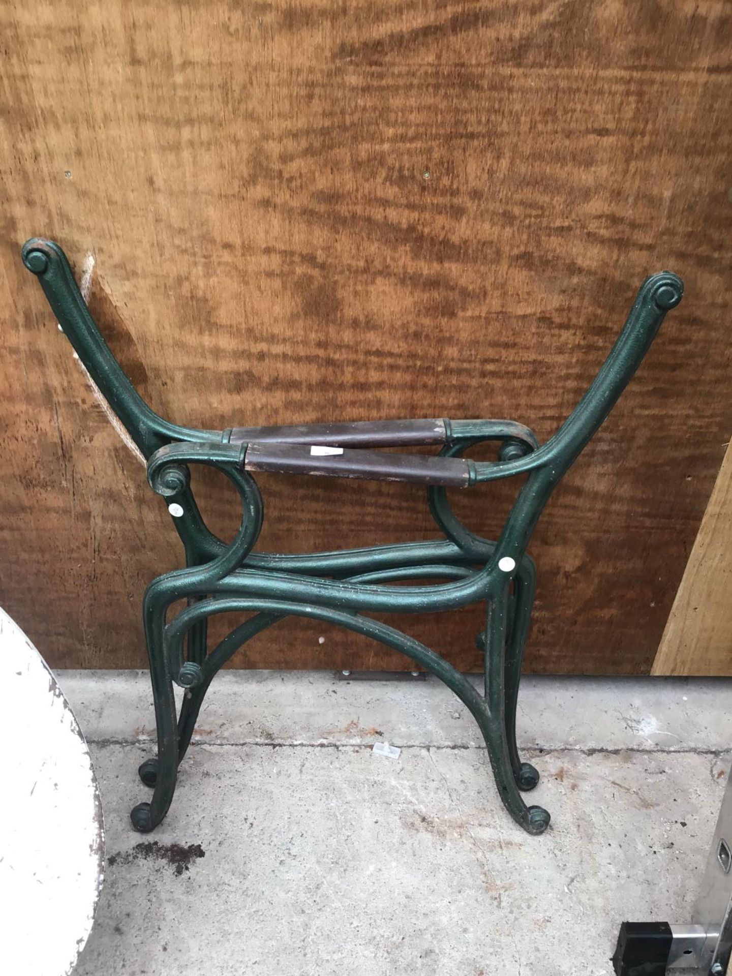 A PAIR OF GREEN CAST IRON BENCH ENDS WITH WOODEN ARM RESTS