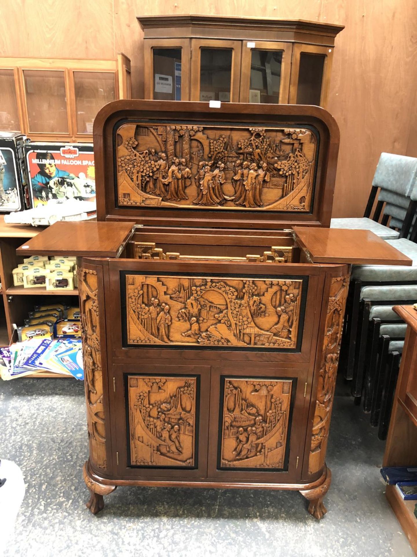 A LARGE CARVED WOODEN ORIENTAL DRINKS CABINET WITH LOWER DOORS REVEALING WINE RACK, UPPER MIRRORED