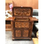 A LARGE CARVED WOODEN ORIENTAL DRINKS CABINET WITH LOWER DOORS REVEALING WINE RACK, UPPER MIRRORED