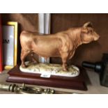 AN UNMARKED CERAMIC BULL FIGURE ON WOODEN BASE, BELIEVED COALPORT