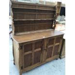 AN OAK DRESSER WITH TWO DOORS AND UPPER PLATE RACK