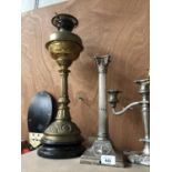 A BRASS OIL LAMP AND SILVER PLATED CORINTHIAN COLUMN CANDLE STICK (2)