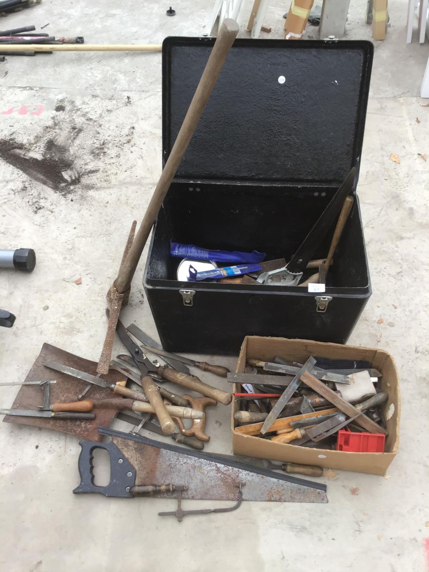 A TOOL BOX CONTAINING VARIOUS TOOLS TO INCLUDE A PICKAXE, SAWS, SHEARS, RASPS ETC