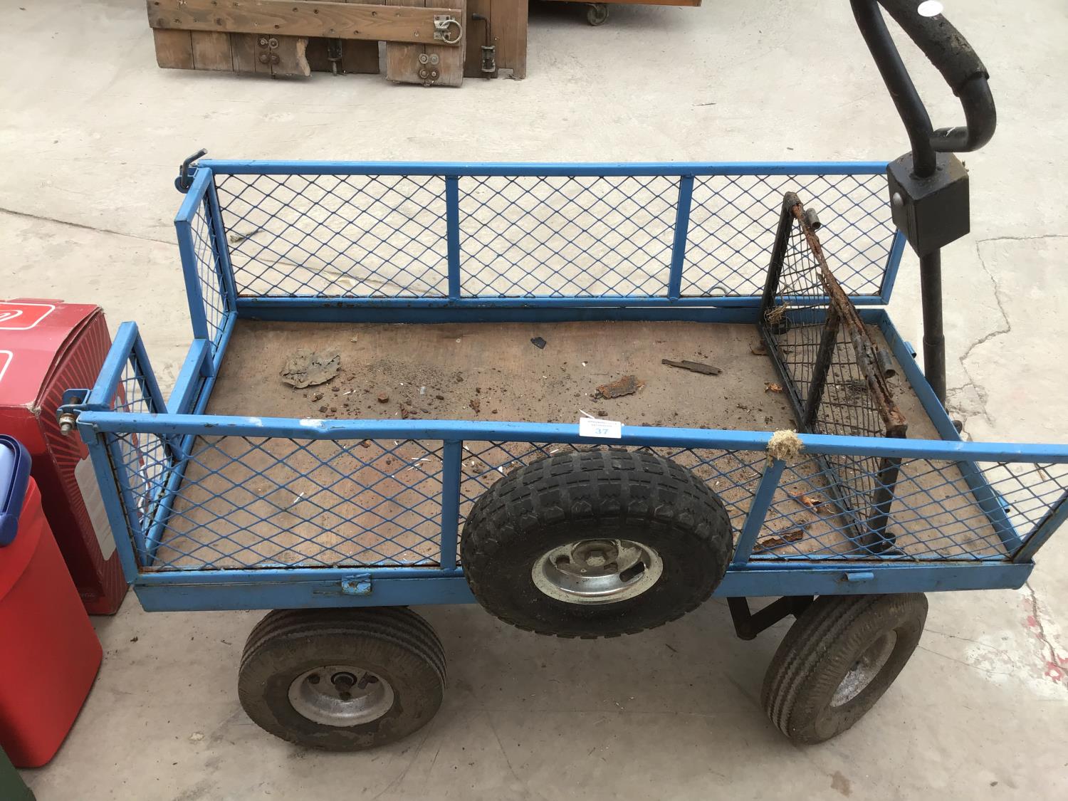A MESH SIDED FOUR WHEEL TROLLEY WITH TYRE WHEELS AND A SPARE TYRE