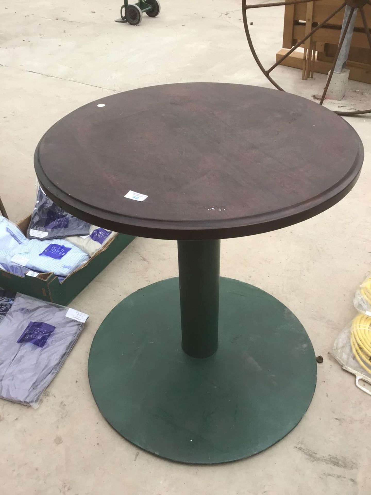 A ROUND WOODEN PUB STYLE TABLE ON A GREEN CAST IRON BASE