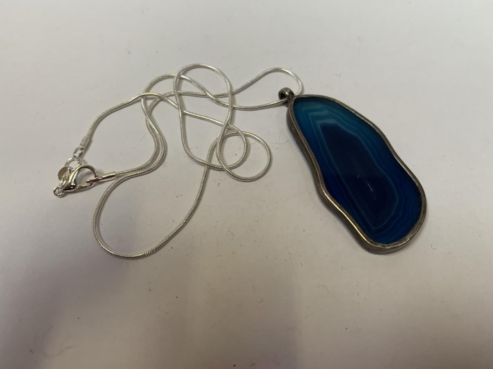 A SILVER NECKLACE WITH LARGE BLUE PENDANT