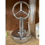 A CHROME MERCEDES METAL EMBLEM ON BASE