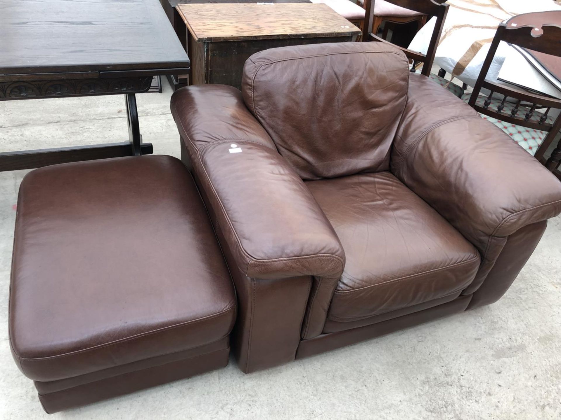 A BROWN LEATHER ARMCHAIR AND FOOTSTOOL
