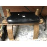 A WOODEN SADDLE STOOL WITH LEATHER TOP