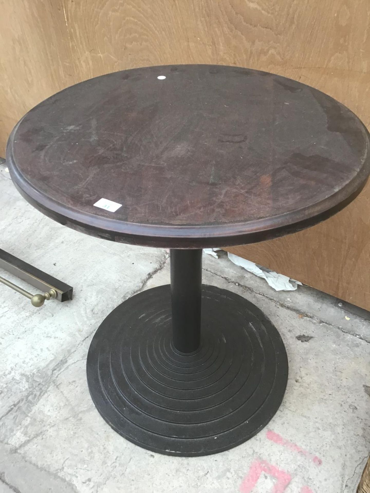 A ROUND WOODEN PUB STYLE TABLE ON A BLACK CAST IRON BASE