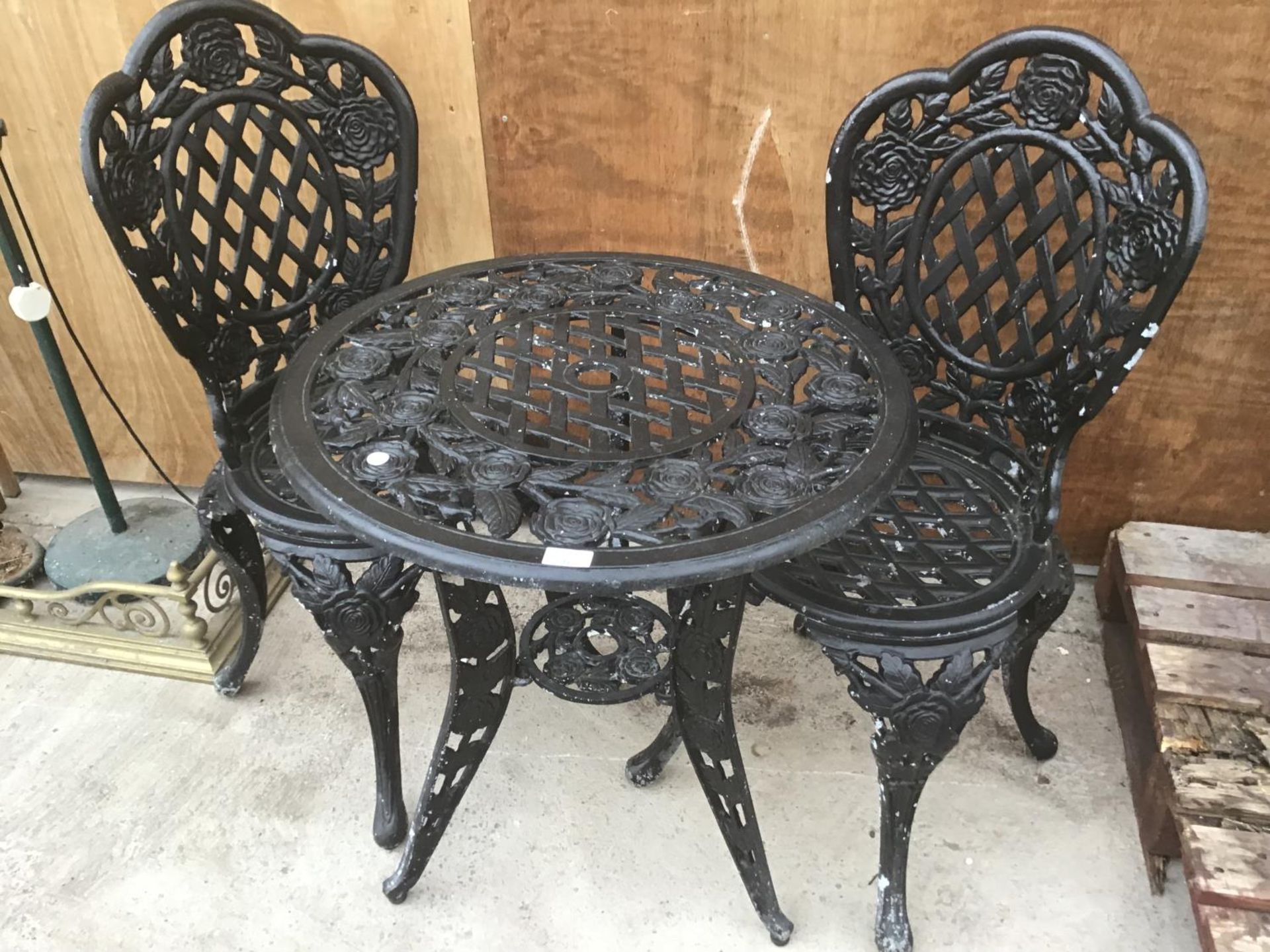 A HEAVY CAST IRON ROSE DESIGN TABLE WITH TWO MATCHING CHAIRS